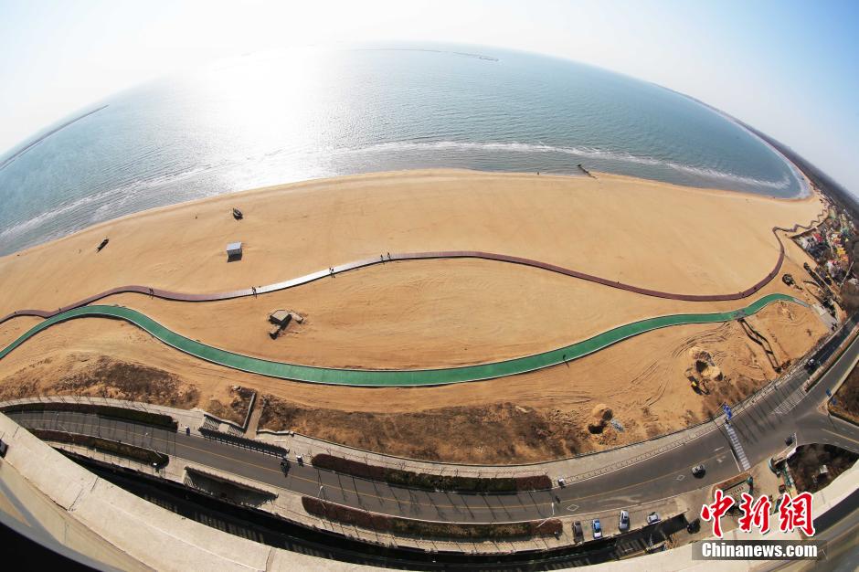 3月13日，秦皇島萬米臨海沙灘木棧道。據(jù)了解，該木棧道全長(zhǎng)約4200米，與北戴河區(qū)原有的7500米木棧道對(duì)接后全線總長(zhǎng)度1.17萬米，整個(gè)木棧道東起秦皇島體育基地游船碼頭，西至北戴河濕地公園，呈波浪形蜿蜒10.4公里海岸線。 中新社發(fā) 曹建雄 攝 CNSPHOTO